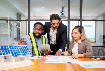 multiethnic coworker discuss meeting on solar roof system project with solar panel house model,...