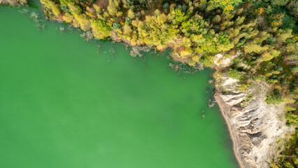 This image is taken from an aerial perspective, capturing the graceful curve of a river as it winds through a lush landscape. The vibrant green waters contrast starkly with the rocky embankment to one