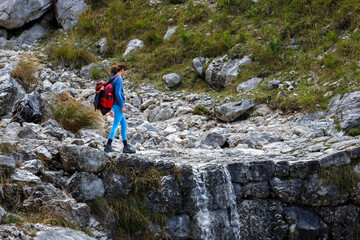Woman Backpack Hiker Walking on a Mountain Trail Path going over a Small Waterfall