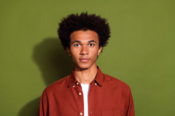 Fototapeta na wymiar Photo of good mood serious confident man with afro hairstyle dressed brown shirt looking at camera isolated on khaki color background