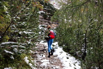 Naklejka na ściany i meble Ascending on a Mountain Trail Path for a Solo Adventurous Woman in Off Season Snowy Landscape