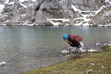 Woman Refreshing Her Face with Cold Water of a mountain Lake after the Effort of the Hike