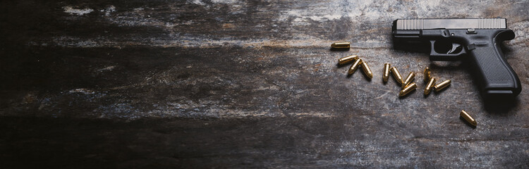 Hand gun with ammunition on dark background. 9 mm pistol military weapon and pile of bullets ammo...