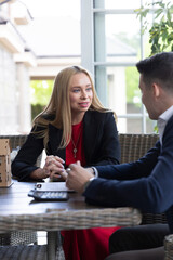 Blonde estate agent shares available house variants with positive client. Realtor offers ideal...