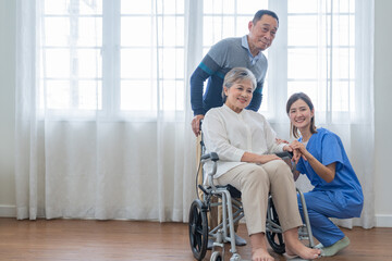 Asian young nurse support couple senior older man and woman in a wheelchair. elderly mature and a group of senior friends living in the hospital. socializing of retired people.