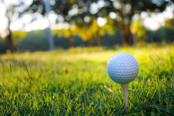 Golf ball set on tee with green bokeh background.