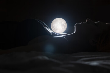 Portrait young beauty woman lying on bed with moon shine behind. Fantasy concept photo