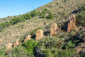 View of the ruins of an old ocher mine and the remains (stone columns) of a railway that was used to transport the ore down to the beach and the supervisor's house near the town of L'Albir in Spain