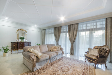 Elegant interior of the living room in neoclassical style. Panoramic window with beautiful curtains. Classic furniture.