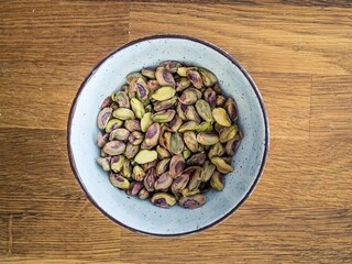 Peeled bare naked pistachio nuts in a white bowl on a wooden table