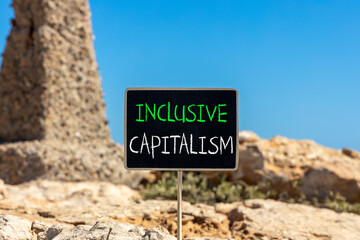 Inclusive capitalism symbol. Concept words Inclusive capitalism on beautiful black chalk blackboard. Beautiful brown stone blue sky background. Business inclusive capitalism concept. Copy space.