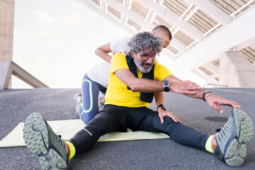 senior sports man stretching legs with help of his personal trainer, concept of active and healthy...