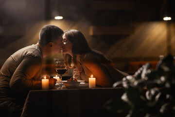 Couple in love celebrating Valentine's day having dinner at home, kissing, view through the window - obrazy, fototapety, plakaty