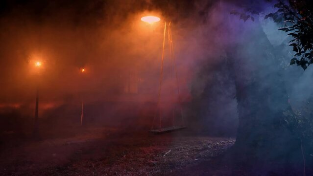 Altalena in giardino avvolta nella nebbia della notte illuminata da dei lampioni con casa sullo sfondo  in 4K