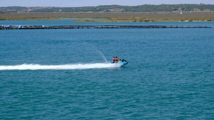 Isla Cristina, Huelva, Spain - August 15, 2023: People on vacation enjoying a quick ride on a jet ski in front of Punta del Caiman beach on Isla Cristina