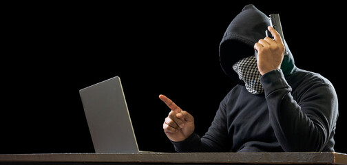 Portrait hacker spy man one person in black hoodie sitting on table looking computer laptop used...