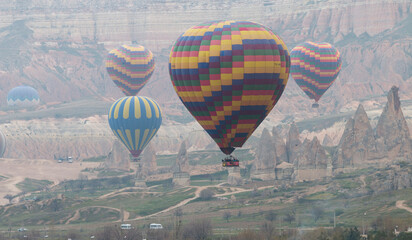 colorful hot air balloons flying over the fairy chimneys of Cappadocia in the early morning, Turkey