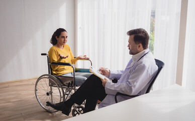 Portrait latin american woman sick sit wheelchair with man doctor caucasian sitting two people...