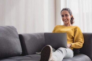 Portrait latin american business woman one person smile happy sitting sofa and looking laptop plan online job work newproject along with looking success future in living room office