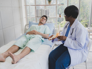 Portrait patient caucasian man with woman nurse carer physical therapist African-American two people sitting talk helping support give advice and holding relax check on leg body inside hospital
