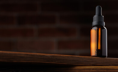 Bottle essential oil for beard men on background dark brick with copy space. Concept barbershop spa...