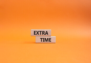 Extra time symbol. Concept word Extra time on wooden blocks. Beautiful orange background. Business...