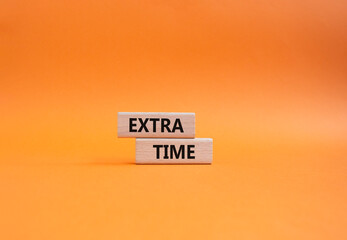 Naklejka premium Extra time symbol. Concept word Extra time on wooden blocks. Beautiful orange background. Business and Extra time concept. Copy space