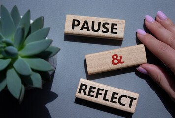 Pause and Reflect symbol. Concept words Pause and Reflect on wooden blocks. Beautiful grey...