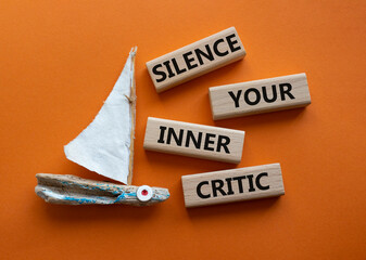 Silence your inner critic symbol. Wooden blocks with words Silence your inner critic. Beautiful orange background with boat. Business and Silence your inner critic concept. Copy space