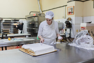 Woman glazing cake in confectionery