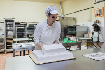 Woman making layered cake in bakery