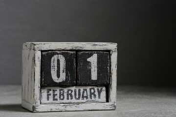 February 01 on wooden calendar, on dark gray background.