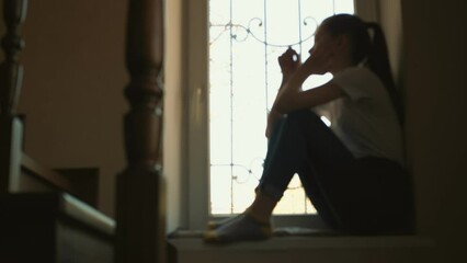 Girl looking out the window in deep thought. Silhouette - Powered by Adobe