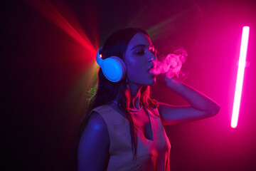 Young woman enjoying night life, she is dancing in headphones and smoking