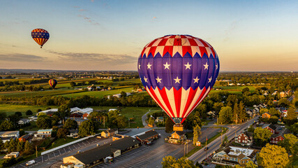 An Aerial View of Multiple Hot Air Balloons Floating Away in Rural Pennsylvania at Sunrise on a...