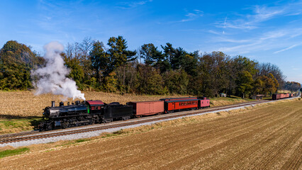 Fototapeta na wymiar An Aerial View of an Antique Restored Steam Passenger - Freight Train Traveling Thru Farmlands on a Autumn Day