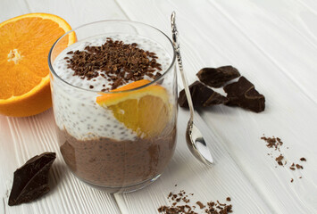 Chocolate pudding with chia seed and orange in the drinking glass  on the white wooden background. Close-up.