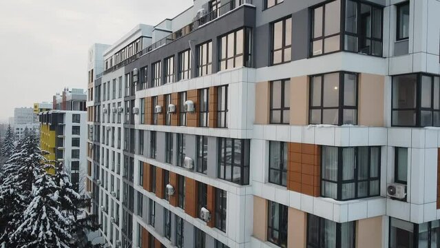 Aerial side view of a newly built modern high-rise apartment building facade. Drone shot of residential building in winter