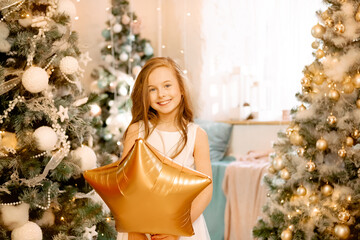 beautiful little girl laughs and stands near the Christmas trees with a star balloon. concept of happy childhood, making a wish for the new year and birthday.