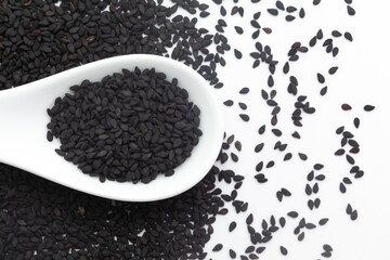 Macro close-up of Black Sesame (Sesamum indicum) Seeds on a white ceramic soup spoon. Top view,...