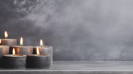 Background for design with copy space. Burning candles on cement background. - obrazy, fototapety, plakaty