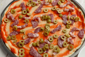 Homemade pizza with green olives and meat slices.
