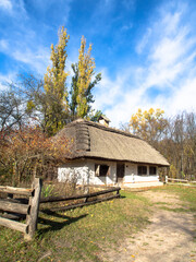 Traditional wooden house with thatched roof and white walls. A small house in a mountain village, Ukraine. Picturesque village in autumn.