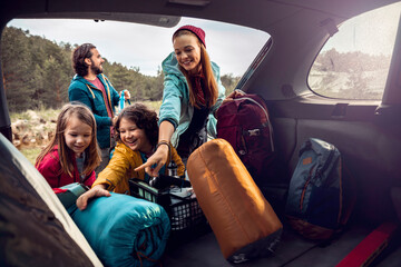 Family taking camping gear out of car