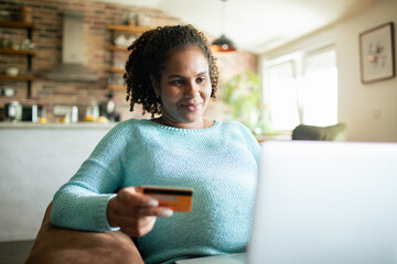 Young pregnant woman using credit card at home