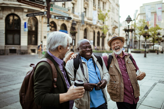 Senior man taking pictures with camera with friends downtown