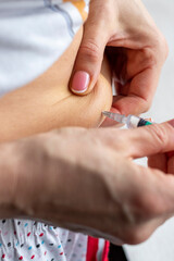 Close up shot of the woman with beautiful hands, preparing hormone medicine and injecting herself to the abdomen with pierced bellybutton. Healthcare