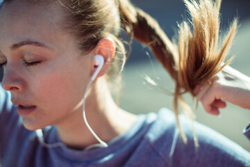 Young female runner tying ponytail before city jog