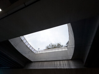 Black and white photo of a concrete underpass, taken from below. The underpass frames the sky and trees visible through a rectangular opening. Hope concept.