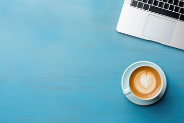 top view of a minimalist workspace featuring a sleek laptop and a cup of coffee on a vibrant blue background, with free space for text or advertising